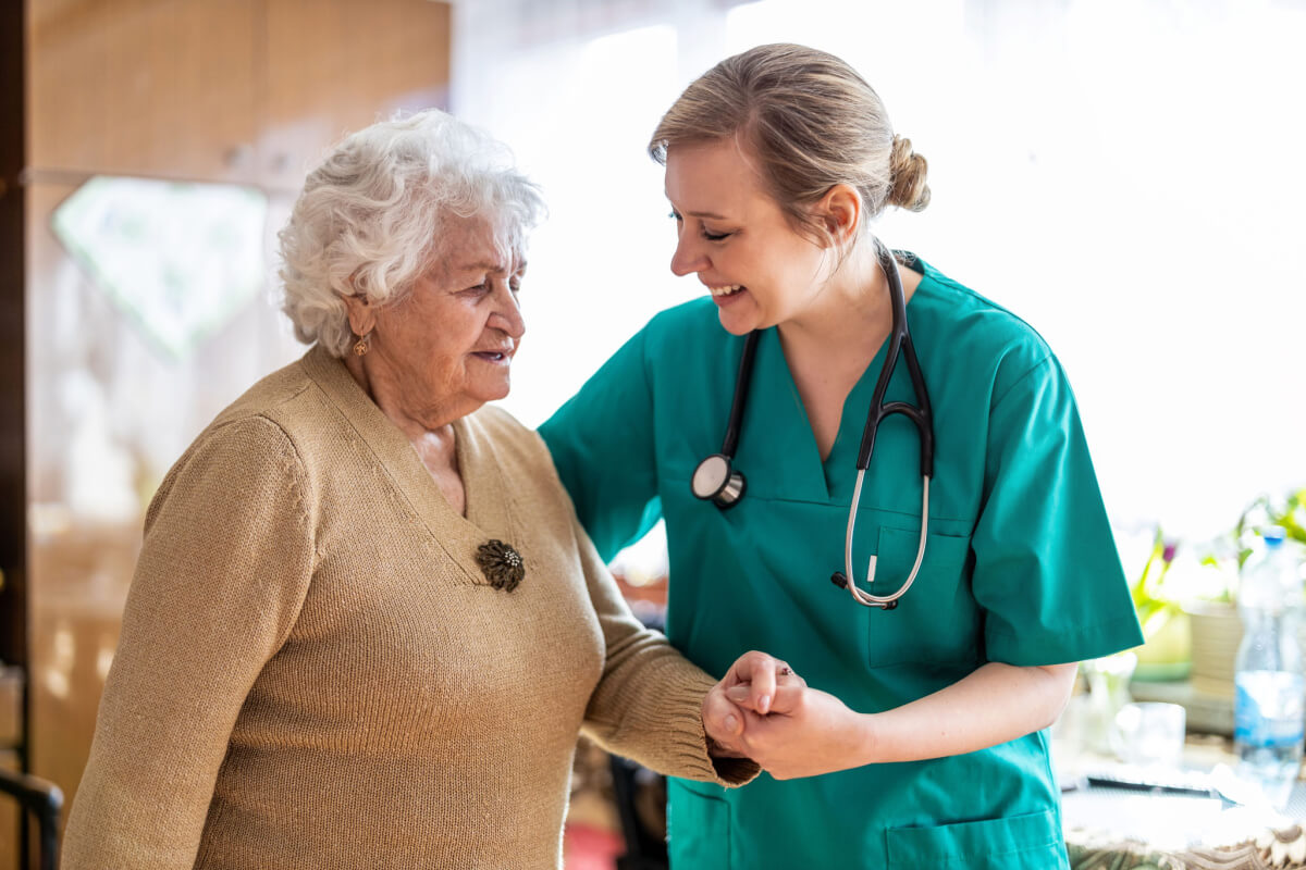 Elderly woman being helped by a nurse